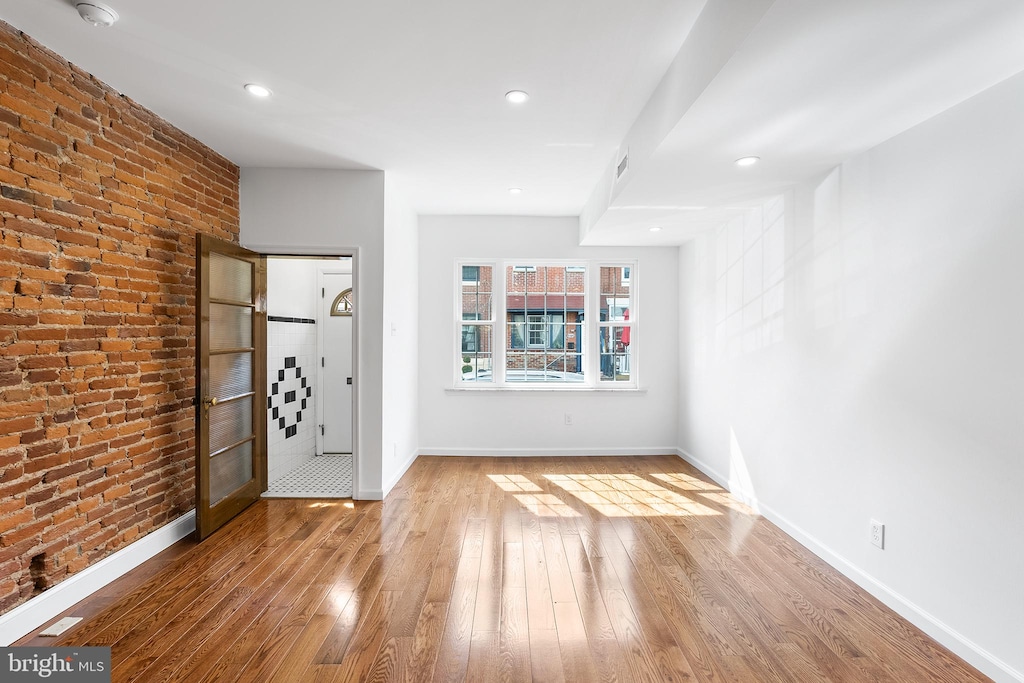 entrance foyer featuring brick wall and light hardwood / wood-style flooring