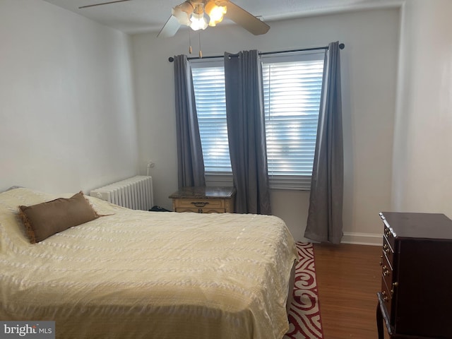 bedroom with dark hardwood / wood-style flooring, ceiling fan, and radiator