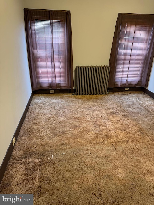 empty room with light colored carpet and radiator