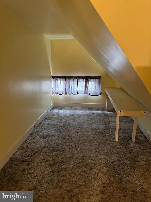 bonus room with vaulted ceiling and dark colored carpet