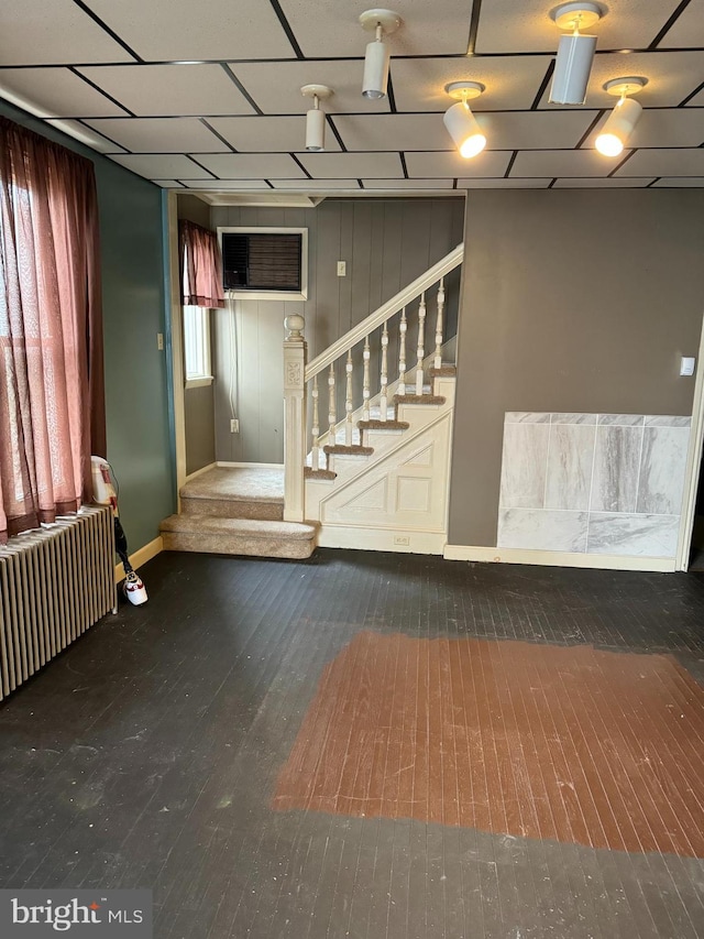 basement with dark hardwood / wood-style floors and radiator