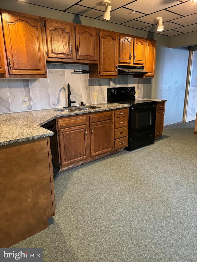 kitchen featuring backsplash, light stone countertops, sink, and black appliances