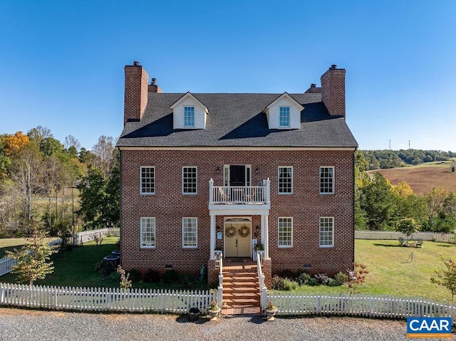 colonial house featuring a balcony and a front lawn