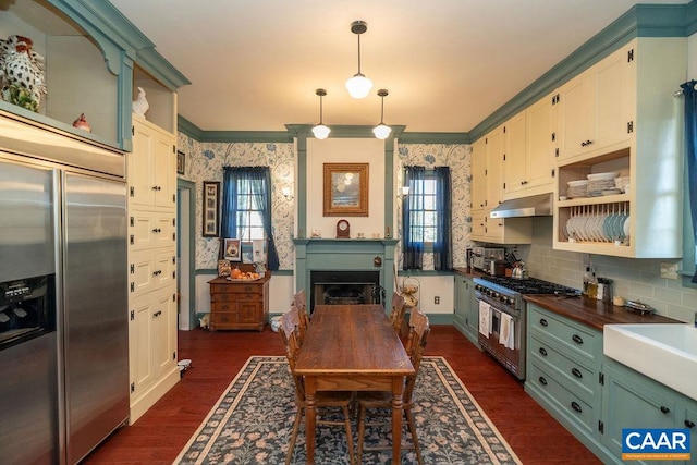 kitchen with pendant lighting, high quality appliances, wooden counters, crown molding, and dark hardwood / wood-style floors