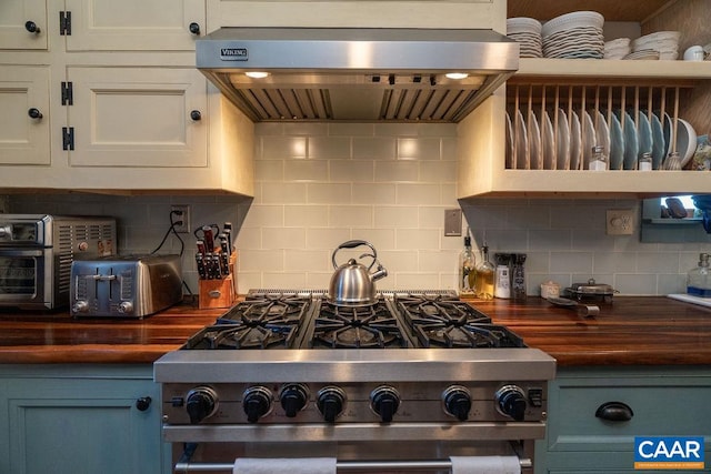 kitchen featuring wooden counters, tasteful backsplash, wall chimney exhaust hood, and stainless steel range with gas stovetop