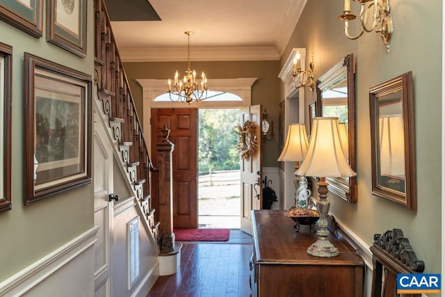 foyer entrance featuring plenty of natural light, an inviting chandelier, dark wood-type flooring, and ornamental molding