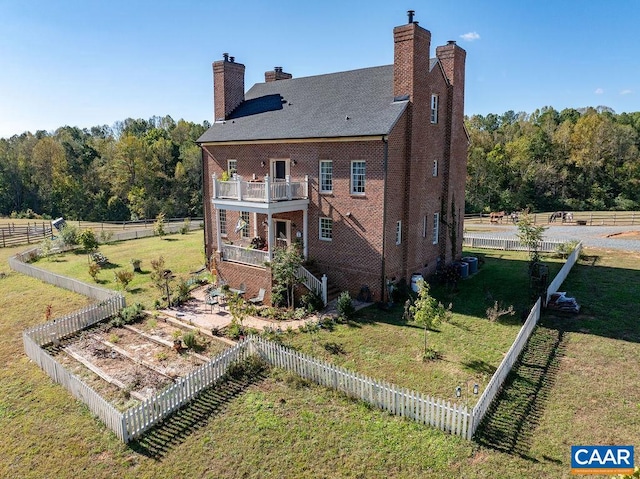 rear view of property featuring a balcony and a lawn