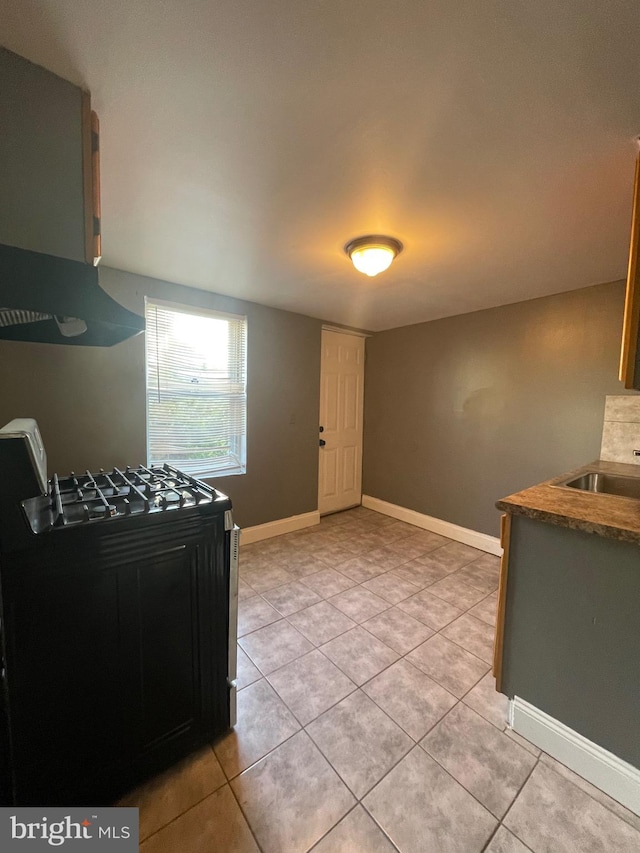 kitchen featuring sink, light tile patterned flooring, extractor fan, and range