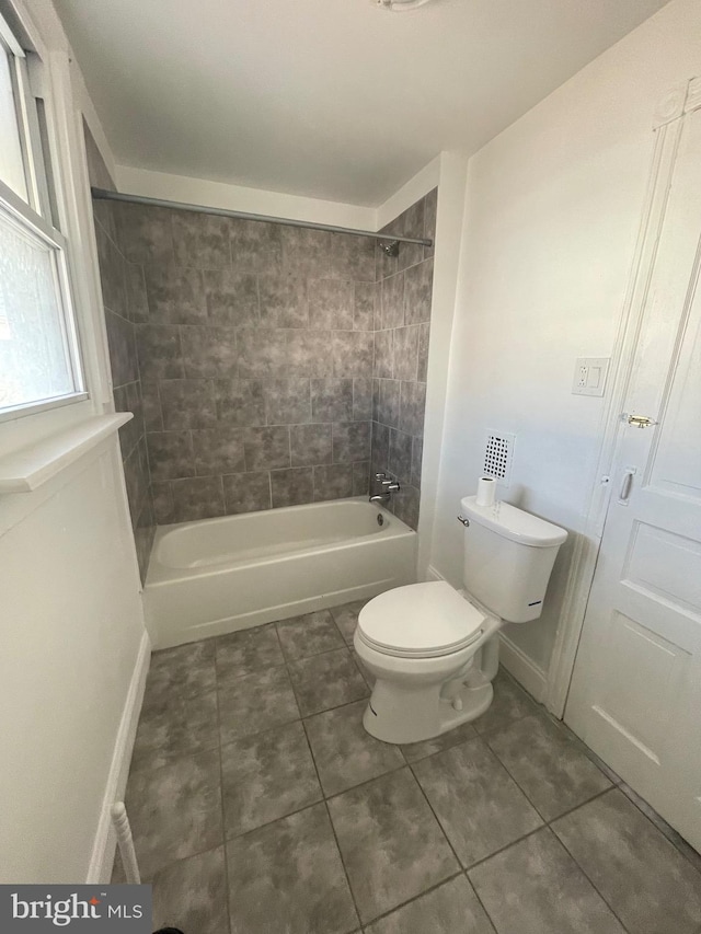 bathroom featuring toilet, tiled shower / bath, and tile patterned flooring