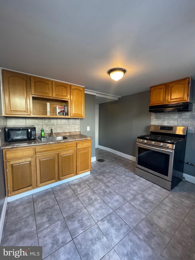 kitchen featuring sink, tasteful backsplash, stainless steel gas range, and dark tile patterned flooring