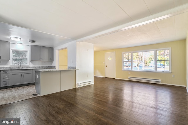 kitchen with a baseboard heating unit, dark hardwood / wood-style floors, light stone counters, and gray cabinetry