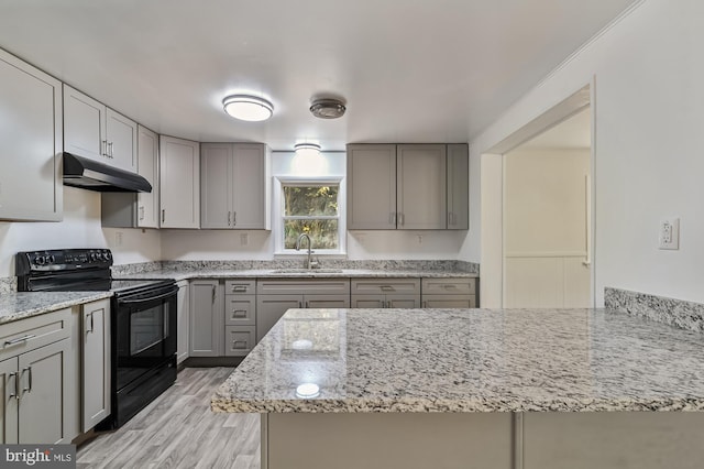 kitchen with light stone countertops, black / electric stove, sink, and light wood-type flooring