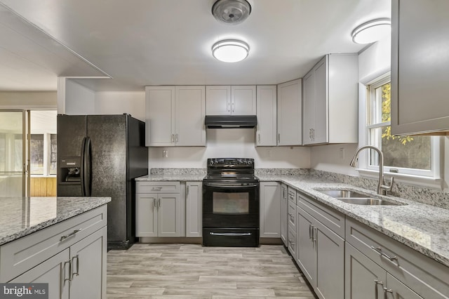 kitchen featuring light hardwood / wood-style floors, black appliances, sink, gray cabinetry, and light stone countertops