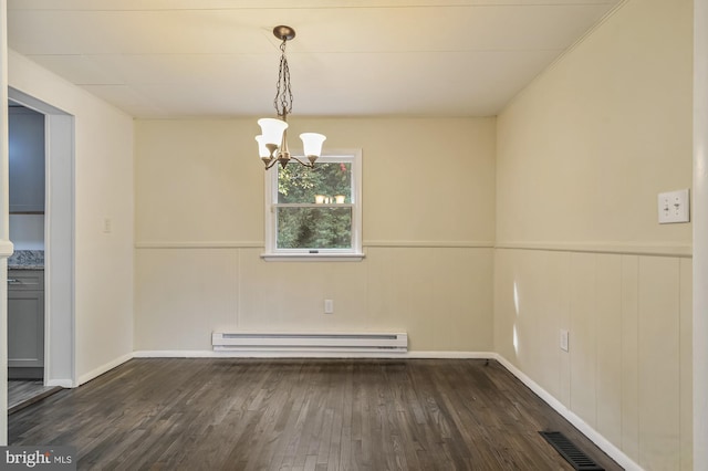 spare room featuring wood walls, dark hardwood / wood-style floors, a baseboard radiator, and a chandelier