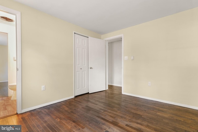 unfurnished bedroom featuring dark hardwood / wood-style flooring and ensuite bath