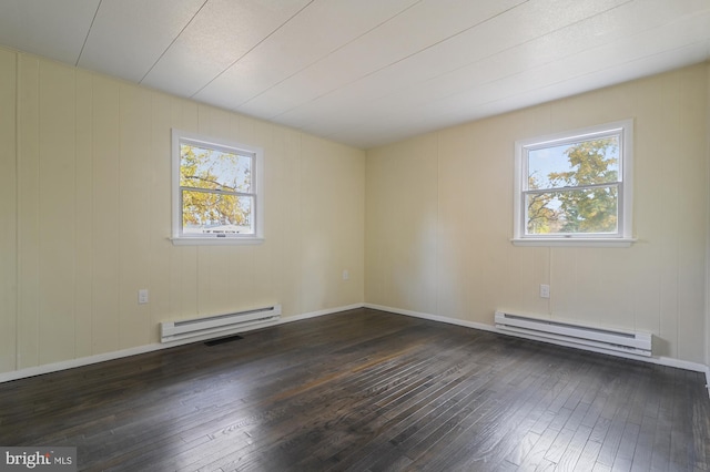 unfurnished room featuring dark hardwood / wood-style flooring, a wealth of natural light, and a baseboard heating unit