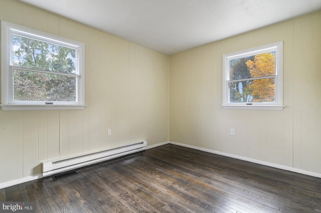 unfurnished room featuring baseboard heating and dark wood-type flooring