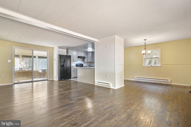 unfurnished living room featuring dark wood-type flooring, a baseboard radiator, and an inviting chandelier