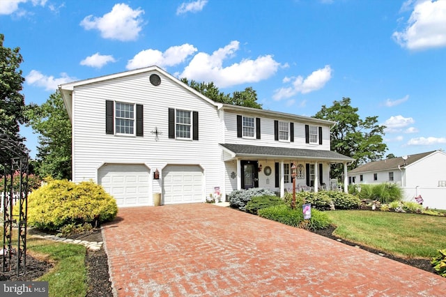 view of front of property featuring a front yard, a garage, and a porch