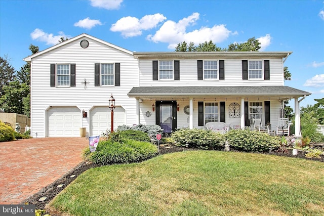 view of front of property featuring covered porch, a garage, and a front lawn