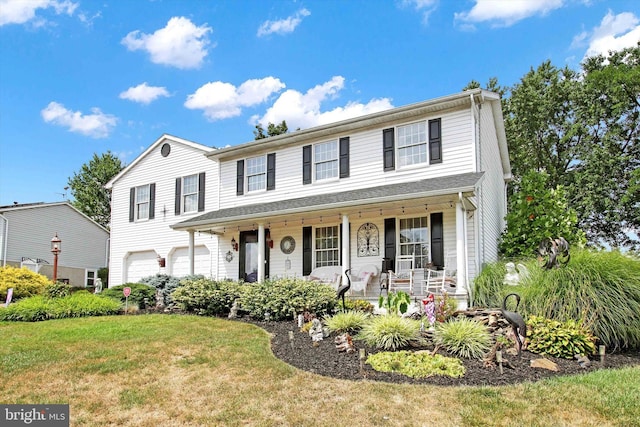 view of front of house featuring a front yard, a porch, and a garage