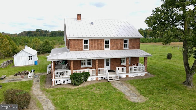 view of front of home featuring an outbuilding, a front lawn, and covered porch