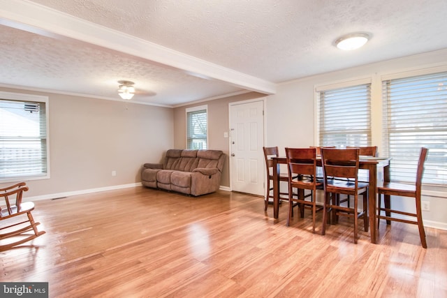 dining room with a textured ceiling, light hardwood / wood-style floors, and ornamental molding