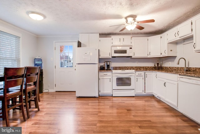 kitchen with white cabinets, a textured ceiling, white appliances, and light hardwood / wood-style floors