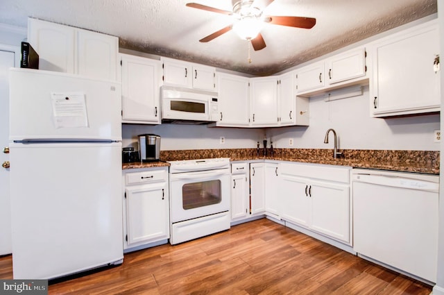 kitchen with a textured ceiling, white appliances, light hardwood / wood-style flooring, dark stone countertops, and white cabinetry