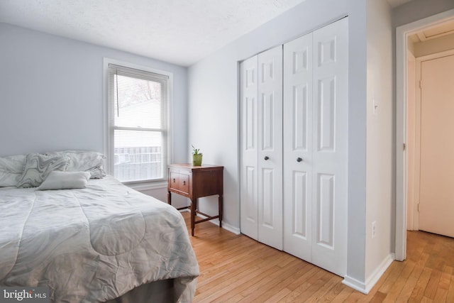 bedroom with light hardwood / wood-style floors, a textured ceiling, and a closet