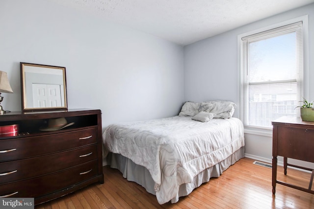 bedroom featuring light hardwood / wood-style floors, a textured ceiling, and multiple windows