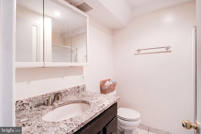 bathroom with toilet, vanity, and tile patterned floors