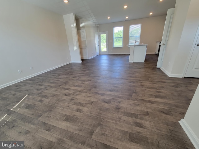 unfurnished living room featuring sink and dark hardwood / wood-style flooring