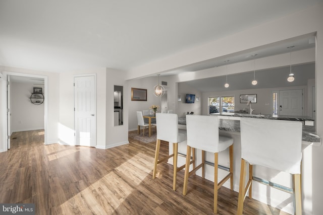 kitchen featuring hardwood / wood-style flooring, a kitchen breakfast bar, kitchen peninsula, and hanging light fixtures