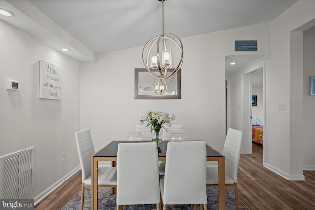 dining space featuring lofted ceiling, dark wood-type flooring, and an inviting chandelier