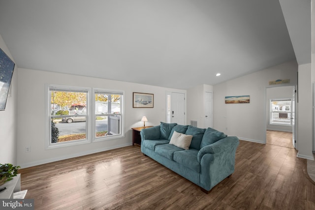 living room featuring lofted ceiling, dark wood-type flooring, and a healthy amount of sunlight