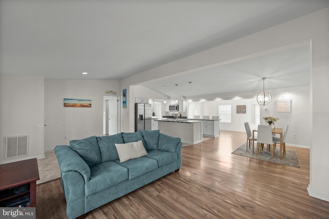 living room featuring a notable chandelier, light hardwood / wood-style floors, and sink