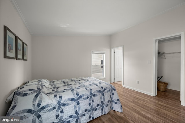 bedroom featuring crown molding, vaulted ceiling, hardwood / wood-style flooring, a spacious closet, and a closet