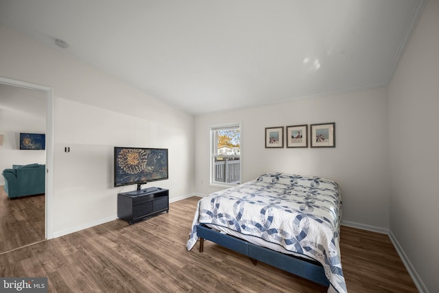 bedroom featuring hardwood / wood-style floors, vaulted ceiling, and ornamental molding