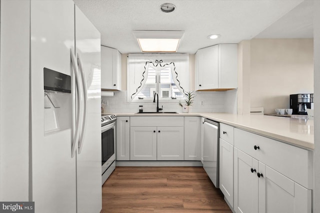 kitchen with appliances with stainless steel finishes, sink, white cabinets, decorative backsplash, and dark hardwood / wood-style floors