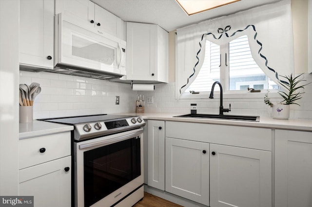 kitchen with white cabinetry, tasteful backsplash, stainless steel range with electric cooktop, and sink