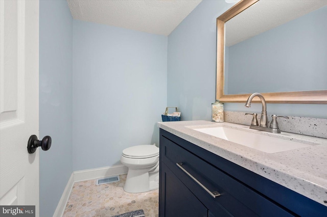 bathroom with toilet, a textured ceiling, vanity, and tile patterned flooring