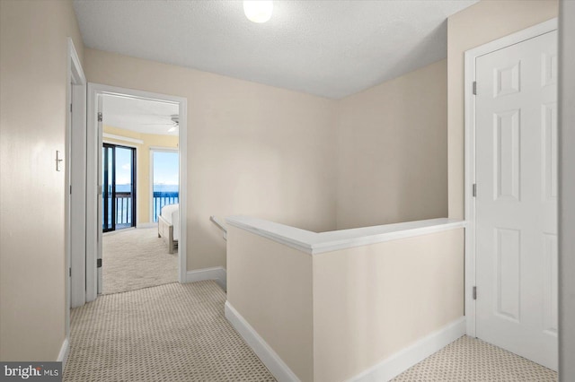 hallway featuring light carpet and a textured ceiling