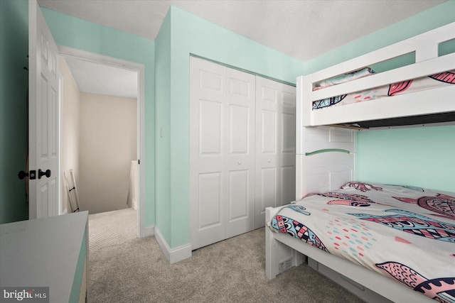 bedroom featuring light carpet, a textured ceiling, and a closet