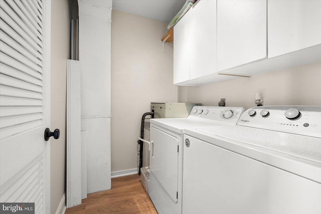 laundry area featuring washer and clothes dryer, dark hardwood / wood-style floors, and cabinets