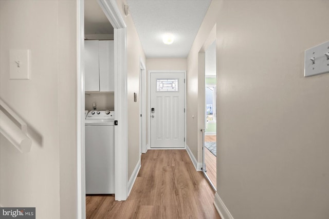 doorway featuring a textured ceiling, light hardwood / wood-style floors, and washer / clothes dryer