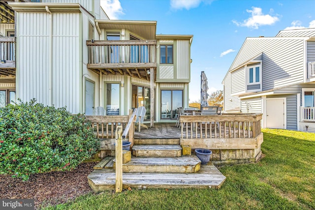 rear view of house featuring a balcony, a deck, and a lawn