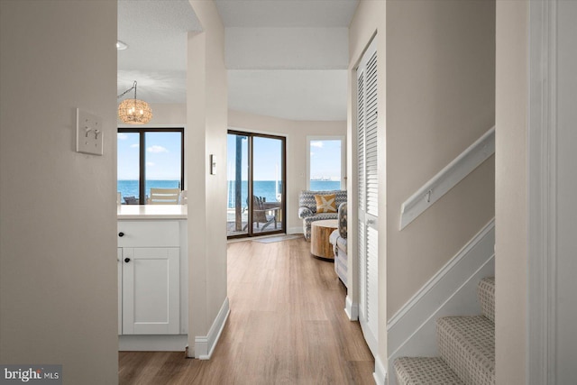 hallway with a chandelier, a water view, and wood-type flooring