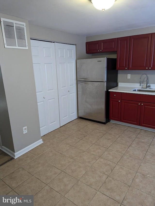 kitchen with stainless steel fridge, sink, and light tile patterned floors