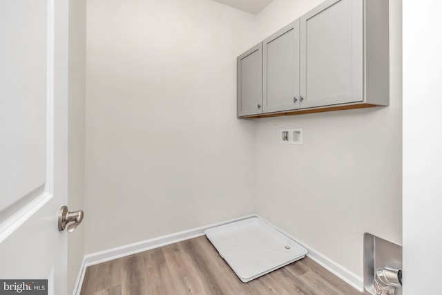 clothes washing area featuring cabinets, light hardwood / wood-style flooring, and washer hookup